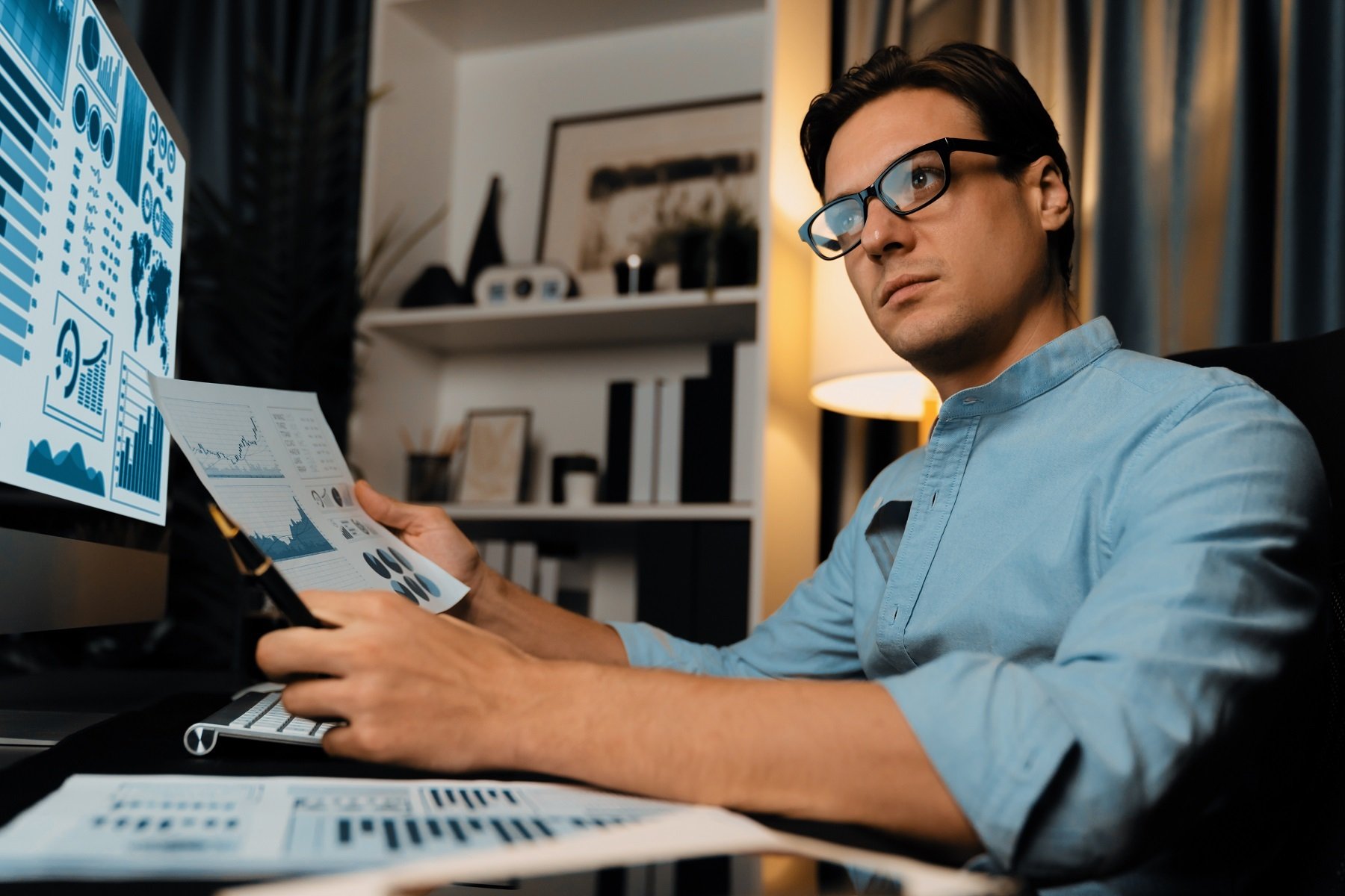 businessman-holding-paperwork-report-database-looking-pc-screen-pecuniary-2